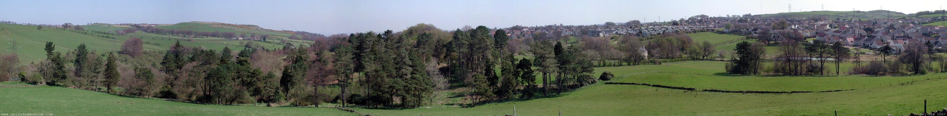 Looking over Neilston from the West, 2005
The trees in the left half of this panorama are the former grounds of Cowden Hall, the house associated with Crofthead Mill.  On the extreme left next to the Pylon are the ruins of the much older 13th century Cowden Hall.  The Fereneze Hills are above the trees.  [url=http://www.streetmap.co.uk/streetmap.dll?G2M?X=246680&Y=656910&A=Y&Z=3/]Map location[/url]
