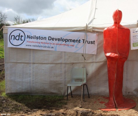 2009, Take me to your leader
The [url=http://www.neilstontrust.co.uk/index.php/] Neilston Development Trust [/url] tent.  It says "Transforming Neilston in an extraordinary way" on the banner . . . and who could argue with them when there is an 8ft red man standing outside.

