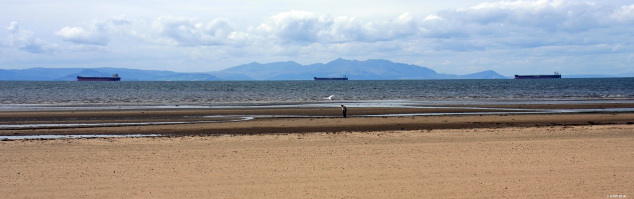 Three Ships, Ayr
Looking out from the sea front at Ayr. Three ships lie at anchor between the coast and the island of Arran in the background.
