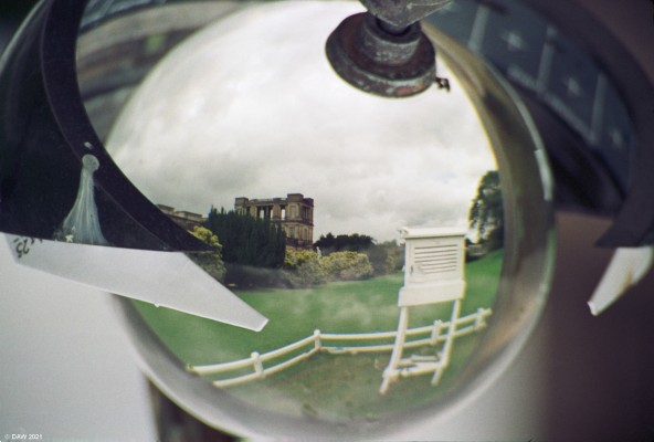 Solar recorder, Chatsworth House, 1993
This unusual photograph is of a sunshine hours recorder in the grounds of Chatsworth house.  The photo has been inverted so the reflection is the right way up.  It consists of a glass sphere surrounded by a strip of card marked with hours of the day.  Any sunlight is focused through the sphere on to the paper creating burn marks when the sun is out.  
