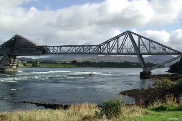 Connel Bridge, Falls of Lora, Loch Etive
This cantilever constructed Railway Bridge over the mouth of Loch Etive was completed in 1903.  It spans 152m over the Loch at the Falls of Lora.  In 1914 it was converted to take both vehicular traffic and trains (but not at the same time!)  After the closure of the railway line in 1966 it was again converted for vehicle only traffic in one direction at a time with traffic lights at either end. At the time this picture was taken in 2002 it was undergoing a major refurbishment.
