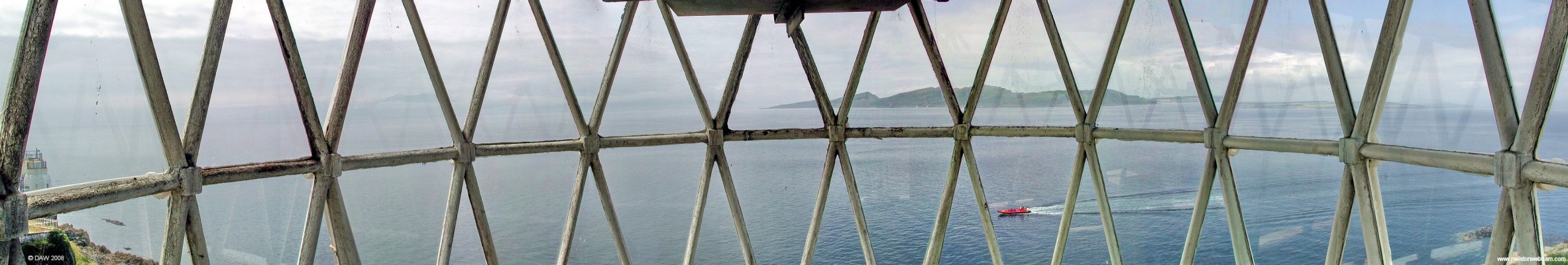 View from top of old Cumbrae Lighthouse
Looking out from inside the lamp room at the top of the Cumbrae Lighthouse.  This tower is now disused but would make a perfect conservatory for someone with lots of money!  The current beacon can be seen in the extreme left side, Arran is mostly hidden by cloud on the left and Bute can be seen in the centre. [url=http://www.streetmap.co.uk/streetmap.dll?G2M?X=213765&Y=651550&A=Y&Z=3/]Map location.[/url]
