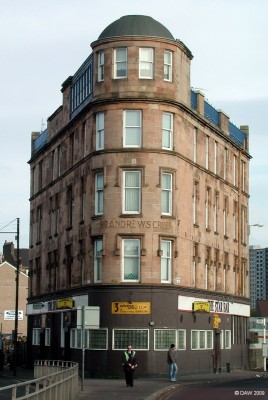 Eglinton Toll, Glasgow
The distinctive triangular shape of the St Andrews Cross building at Eglinton Toll on the south side of Glasgow, probably dating from around 1888.   Note the frosted glass windows of the Star Bar on the ground floor, this used to be a tradition so that good people wouldn't be corrupted by seeing all those people drinking inside.  [url=http://www.streetmap.co.uk/map.srf?X=258470&Y=663467&A=Y&Z=115/] Map location. [/url]

