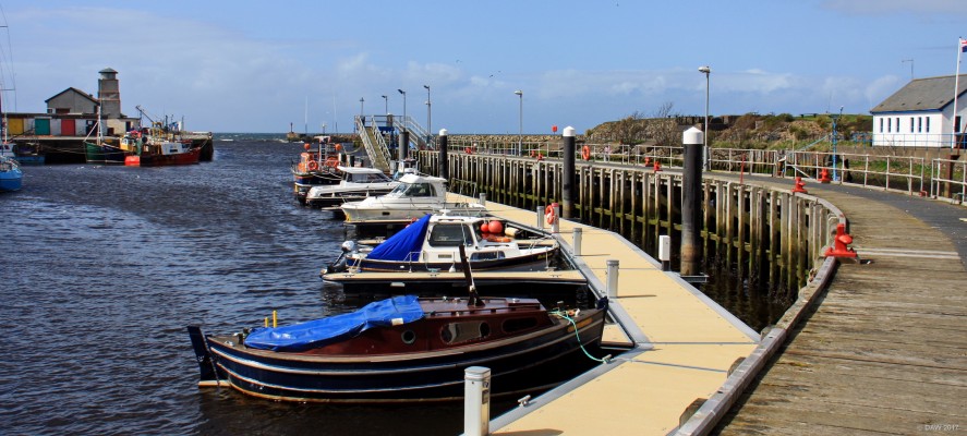 The inner harbour, Girvan
Girvan has had a harbor for a long time, this wooden part is a more recent addition.  Next to the white building on the right there was a coal port.  In 1847 the harbor supported 34 fishing boats and 90 fishermen.  Between 1869-70 the harbor was rebuilt and again extended in 1881-3.  One modern addition on the left is the building that looks a bit like a lighthouse, it is in fact a sewerage treatment plant.

