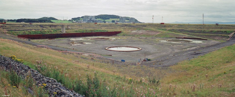 Hunterston Construction Yard, 1988
A view looking west from the edge of the contruction yard.  At this time both Hunterston A (right) and Hunterston B (left) Nuclear Power Stations are still in use.  At the time this photo was taken the yard was disused, the 3 circles a witness to the last job, the Maureen Alpha gravity base.
