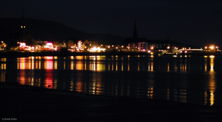 Largs by night
A view along the sea front from the north shore.  Taken at the time of the annual Viking festival when the shows are in the car park near the pier. 
