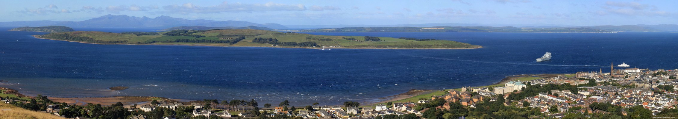 Panoramic view over Cumbrae from above Largs, 2010
On the left is the Wee Cumbrae, next is the Great Cumbrae, the mountains in the distance are on the Isle of Arran.  Immediately behind the Great Cumbrae is the Island of Bute.  RFA Largs Bay is anchored in Largs bay on its last visit to Largs before being sold to Australia. [url=http://www.streetmap.co.uk/map.srf?X=221441&Y=658511&A=Y&Z=120/] Map location. [/url]
