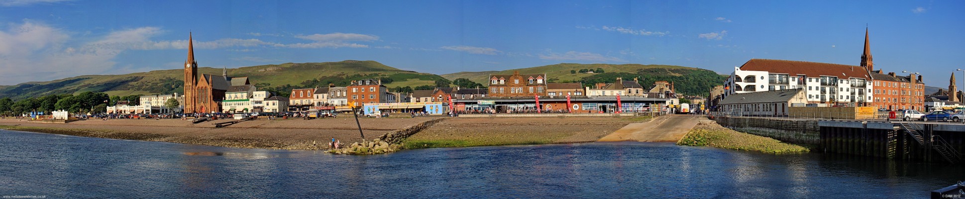 Largs Seafront Panorama, 2010
A view from the pier on a sunny evening.  From the extreme left going right the church spires you can see are St John's, The Clark Memorial and St Columba's.  The stone wall in the centre that looks like a break water is actually the remains of the old fish Quay and would pre-date the larger pier.  The slipway is used by the car ferry over to the Island of Millport.  [url=http://www.streetmap.co.uk/map.srf?X=220041&Y=659496&A=Y&Z=120/] Map location. [/url]
