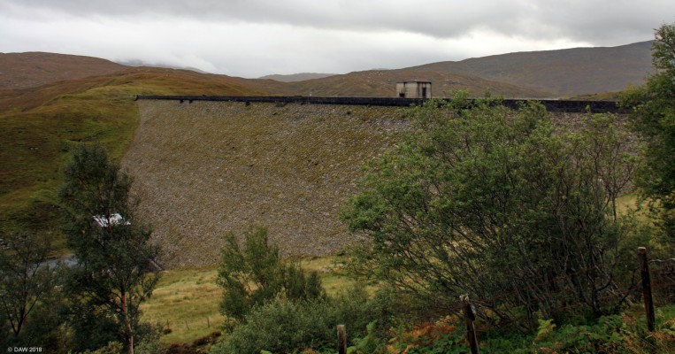 Loch Quoich Dam
Built for the North of Scotland Hydro Electric Board in 1955 this Dam forms part of the great Glen Hydro Scheme.  At the time it was built it was the largest of its type at 125ft high and 1050ft long.  It is earth fill, re-enforced by concrete with a natural stone facing.  Through the trees you can just make out a building, this is the compensation turbine hall that generates a small amount of electricity from the water passed through the dam to allow the flow of the river Garry. 
