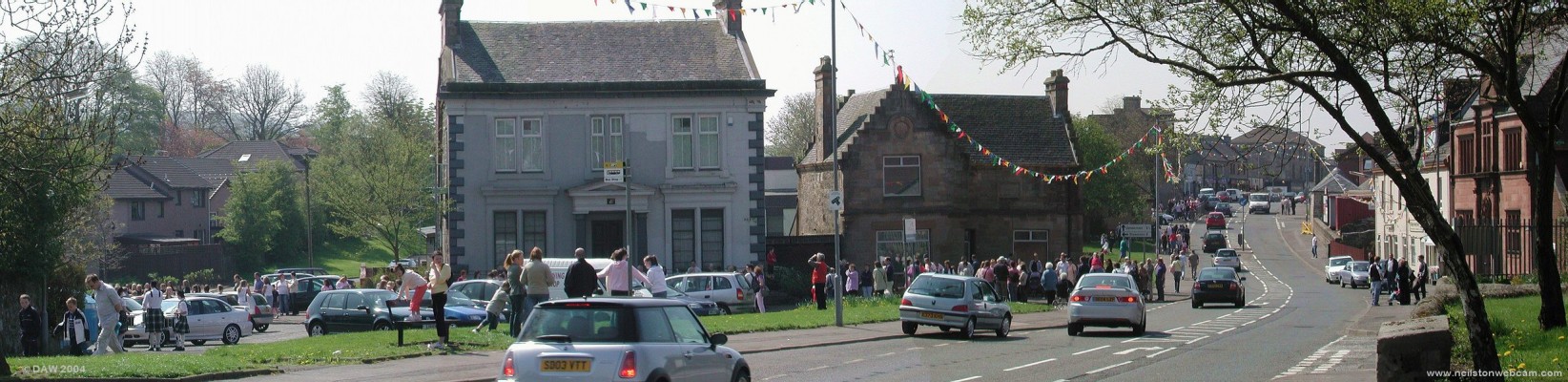 Main Street Panorama, May 2004
Taken on May 1st 2004 as the crowds gather to watch the Parade through the Village to the Neilston Show.  The Masonic Lodge is the grey building near the centre of the picture and the Glen Halls are on the extreme right.  
