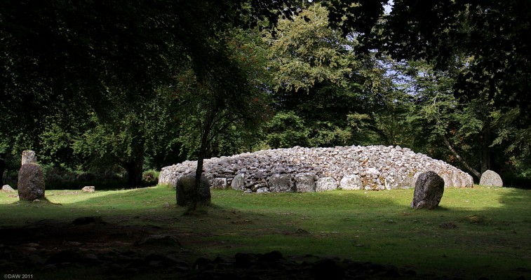 The North east Passage Grave, Clava
Dating from some 2,500 B.C. it would originally have been around 3m high with a covered chamber in the centre created by overlapping stones.  After a period of use the chamber was closed and the cairn was surounded by a ring of standing stones, the highest towards the entrance and where the winter sun rises.
