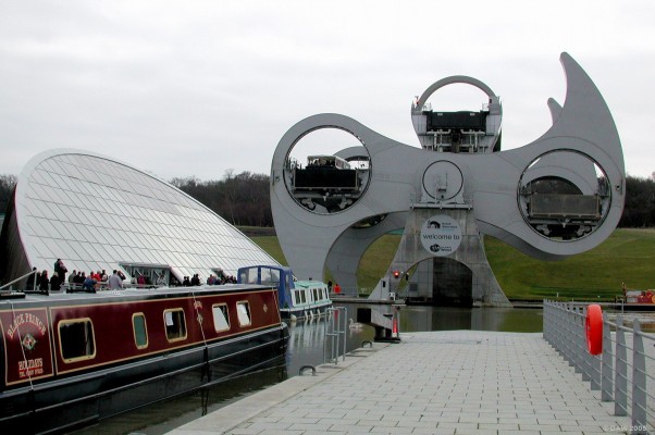 The Falkirk Wheel, midway
This view shows the wheel midway, each caisson can carry up to 4 20m barges.  The structure is so efficient that it only requires a few kilowatts of power to rotate, the same power that a kettle uses.  The visitor centre is the glass structure on the left.
