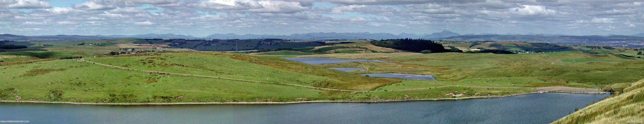 North eastern panoramic view over Long Loch
At only 282m James's Hill gives a surprisingly good view over East Renfrewshire and beyond.  In the foreground is Long Loch and behind that Harelaw Dam.  On the left Glasgow can be seen in the distance.  The Neilston Pad is where the dark patch of trees are and to the right of that can be seen the familiar 'shoulder' outline of Ben Lomond.  [url=http://www.streetmap.co.uk/streetmap.dll?G2M?X=248640&Y=652825&A=Y&Z=3/] Map location.[/url]
