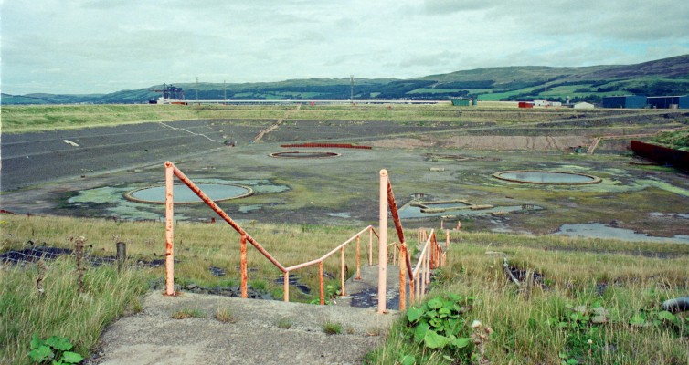 Hunterston Construction Yard, 1988
A view inside the construction basin at Hunterston.  At the time this photo was taken in 1988 the yard had been abandoned, the three largs circles you see are a witness to the last job which was the Gravity base/Oil storage structure for the Maureen Alpha platform in the North Sea.  Maureen operated from 1979 until 1999. [url=http://streetmap.co.uk/map.srf?X=218502&Y=652972&A=Y&Z=120/] Map location. [/url]
